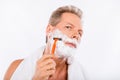 Handsome happy man with towel shaving himself with a razor