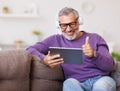 Handsome happy senior man waving by hand while talking online on digital tablet with family Royalty Free Stock Photo