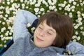 Handsome happy smiling young boy lying and sleeping or dreaming on summer meadow green grass with daisy. Attractive smiling teen Royalty Free Stock Photo