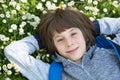 Handsome happy smiling young boy lying on summer meadow green grass with daisy. Attractive smiling teen boy posing over nature Royalty Free Stock Photo