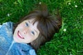 Handsome happy smiling young boy lying on summer meadow green grass with daisy. Attractive smiling teen boy posing over nature Royalty Free Stock Photo