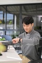 Handsome Asian male developer or office worker checking time on his smartwatch at his desk Royalty Free Stock Photo