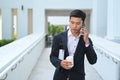 Handsome having phone conversation while walking outside modern office building