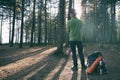 Handsome hiker adventurer man in felt hat with backpack and ÃÂamping gear standing in pine woods at sunset. Adventure, active Royalty Free Stock Photo