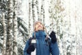 Handsome hiker man in warm clothes with thermos travel in winter forest in snowy day. He looks up and smile. Season concept. Copy