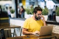 Handsome hipster bearded man drink coffee at the coworking space and work with laptop computer and internet free wifi connection