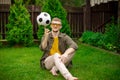 Handsome man sits on lawn spinning soccer ball on index finger, sports betting Royalty Free Stock Photo