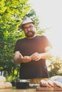 Handsome hipster man preparing meat and zucchini burgers, bbq summer garden food Royalty Free Stock Photo