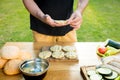 Handsome hipster man preparing meat and zucchini burgers, bbq summer garden food Royalty Free Stock Photo