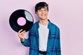 Handsome hipster young man holding vinyl disc looking positive and happy standing and smiling with a confident smile showing teeth Royalty Free Stock Photo