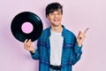 Handsome hipster young man holding vinyl disc smiling happy pointing with hand and finger to the side Royalty Free Stock Photo