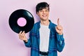 Handsome hipster young man holding vinyl disc smiling with an idea or question pointing finger with happy face, number one Royalty Free Stock Photo