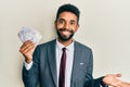 Handsome hispanic business man with beard holding swedish krona banknotes celebrating achievement with happy smile and winner Royalty Free Stock Photo