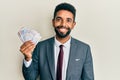 Handsome hispanic business man with beard holding swedish krona banknotes looking positive and happy standing and smiling with a Royalty Free Stock Photo