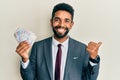 Handsome hispanic business man with beard holding swedish krona banknotes pointing thumb up to the side smiling happy with open Royalty Free Stock Photo