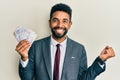 Handsome hispanic business man with beard holding swedish krona banknotes screaming proud, celebrating victory and success very Royalty Free Stock Photo