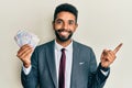 Handsome hispanic business man with beard holding swedish krona banknotes smiling happy pointing with hand and finger to the side Royalty Free Stock Photo