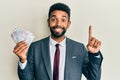 Handsome hispanic business man with beard holding swedish krona banknotes smiling with an idea or question pointing finger with Royalty Free Stock Photo