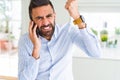 Handsome hispanic business man having a conversation talking on smartphone annoyed and frustrated shouting with anger, crazy and Royalty Free Stock Photo