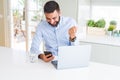 Handsome hispanic business man using laptop and smartphone screaming proud and celebrating victory and success very excited, Royalty Free Stock Photo