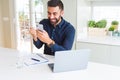 Handsome hispanic business man using smartphone and laptop at the office screaming proud and celebrating victory and success very Royalty Free Stock Photo