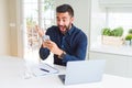 Handsome hispanic business man using smartphone and laptop at the office very happy and excited, winner expression celebrating Royalty Free Stock Photo