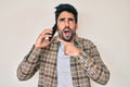 Handsome hispanic man with beard having conversation talking on the smartphone angry and mad screaming frustrated and furious, Royalty Free Stock Photo