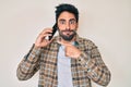 Handsome hispanic man with beard having conversation talking on the smartphone puffing cheeks with funny face Royalty Free Stock Photo