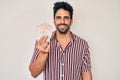 Handsome hispanic man with beard holding united kingdom pounds looking positive and happy standing and smiling with a confident