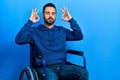 Handsome hispanic man with beard sitting on wheelchair relax and smiling with eyes closed doing meditation gesture with fingers Royalty Free Stock Photo