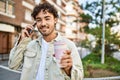 Handsome hispanic man with beard smiling happy outdoors on a sunny day having a conversation speaking on the phone Royalty Free Stock Photo