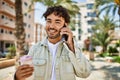 Handsome hispanic man with beard smiling happy outdoors on a sunny day having a conversation speaking on the phone Royalty Free Stock Photo