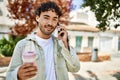 Handsome hispanic man with beard smiling happy outdoors on a sunny day having a conversation speaking on the phone Royalty Free Stock Photo