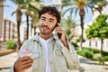 Handsome hispanic man with beard smiling happy outdoors on a sunny day having a conversation speaking on the phone Royalty Free Stock Photo