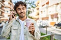 Handsome hispanic man with beard smiling happy outdoors on a sunny day having a conversation speaking on the phone Royalty Free Stock Photo