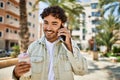 Handsome hispanic man with beard smiling happy outdoors on a sunny day having a conversation speaking on the phone Royalty Free Stock Photo