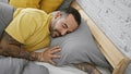 Handsome hispanic man with beard and tattoos sleeping peacefully in a modern bedroom Royalty Free Stock Photo
