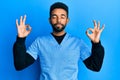 Handsome hispanic man with beard wearing blue male nurse uniform relax and smiling with eyes closed doing meditation gesture with Royalty Free Stock Photo