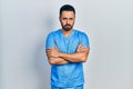 Handsome hispanic man with beard wearing blue male nurse uniform skeptic and nervous, disapproving expression on face with crossed