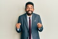 Handsome hispanic man with beard wearing business suit and tie excited for success with arms raised and eyes closed celebrating Royalty Free Stock Photo