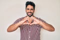 Handsome hispanic man with beard wearing casual clothes smiling in love showing heart symbol and shape with hands