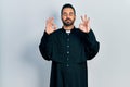 Handsome hispanic man with beard wearing catholic priest robe relaxed and smiling with eyes closed doing meditation gesture with Royalty Free Stock Photo