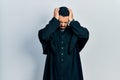 Handsome hispanic man with beard wearing catholic priest robe suffering from headache desperate and stressed because pain and Royalty Free Stock Photo