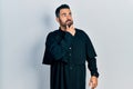 Handsome hispanic man with beard wearing catholic priest robe thinking worried about a question, concerned and nervous with hand