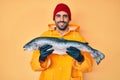 Handsome hispanic man with beard wearing fisherman equipment smiling with a happy and cool smile on face