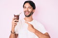 Handsome hispanic man drinking mate infusion smiling happy pointing with hand and finger Royalty Free Stock Photo