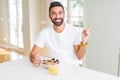 Handsome hispanic man eating healthy breakfast in the morning at home very happy pointing with hand and finger to the side Royalty Free Stock Photo