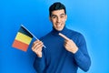 Handsome hispanic man holding belgium flag smiling happy pointing with hand and finger Royalty Free Stock Photo