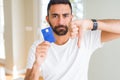 Handsome hispanic man holding credit card with angry face, negative sign showing dislike with thumbs down, rejection concept Royalty Free Stock Photo