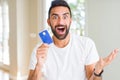 Handsome hispanic man holding credit card very happy and excited, winner expression celebrating victory screaming with big smile Royalty Free Stock Photo